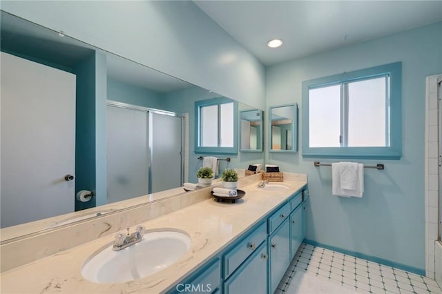 bathroom featuring a shower with door, plenty of natural light, double vanity, and a sink