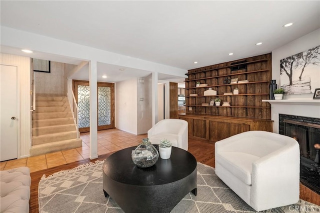 sitting room with recessed lighting, stairs, wood finished floors, and a premium fireplace