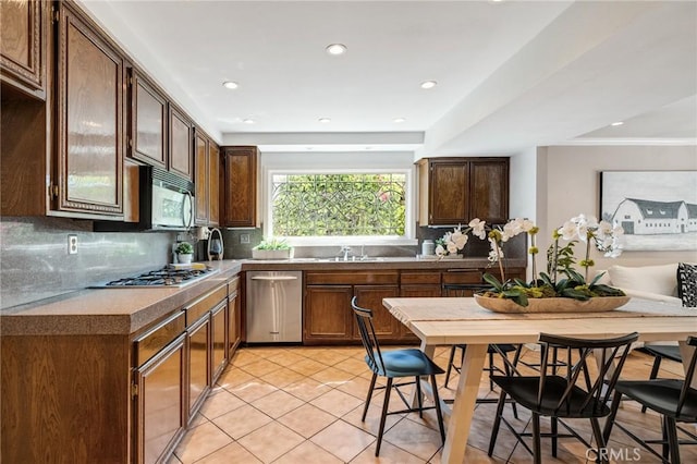 kitchen featuring recessed lighting, light tile patterned flooring, decorative backsplash, stainless steel appliances, and a sink