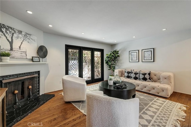 living room with recessed lighting, a high end fireplace, and wood finished floors