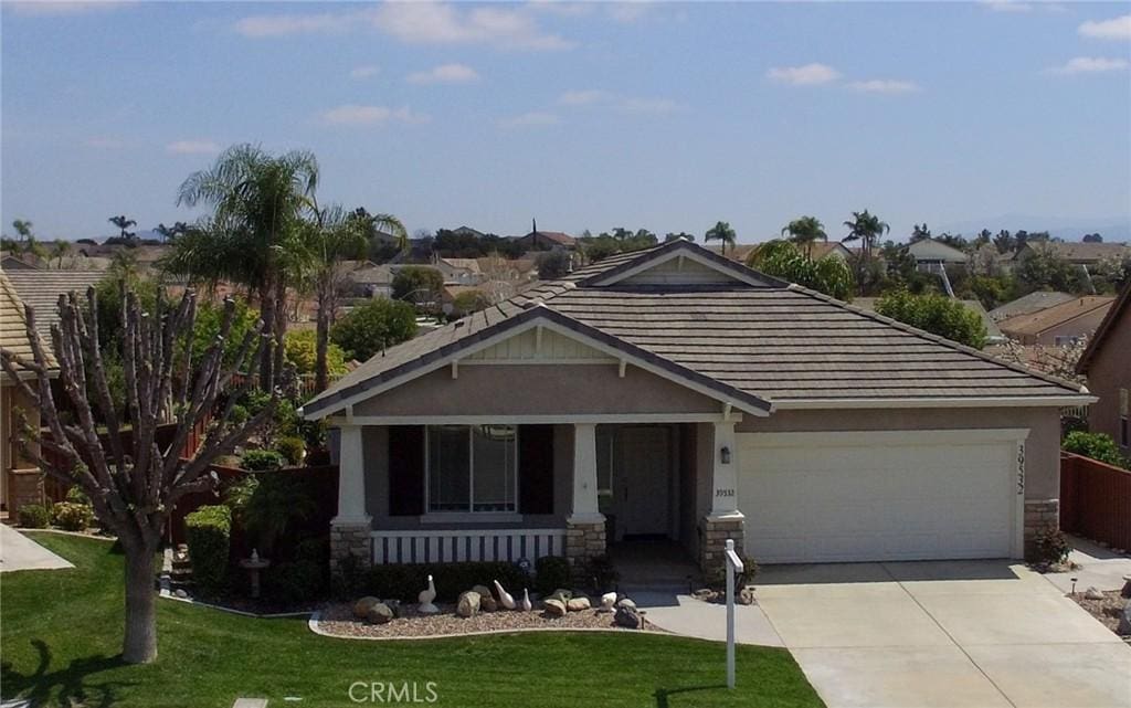 39532 Corbett Canyon Cir, Murrieta, CA 92563 - craftsman-style home with concrete driveway, stone siding, a tiled roof, a front lawn, and a garage