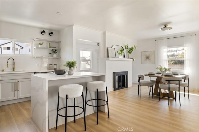 kitchen with a wealth of natural light, a kitchen bar, a sink, and light wood-style floors