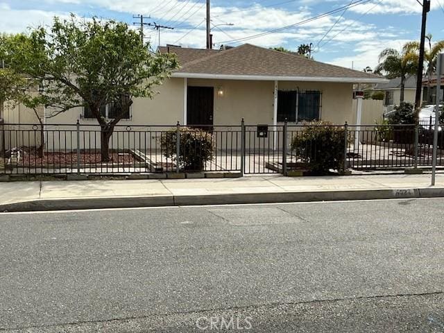 view of front of property featuring a shingled roof, fence private yard, and stucco siding