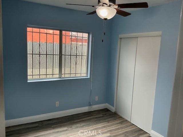 unfurnished bedroom with a closet, baseboards, a ceiling fan, and wood finished floors