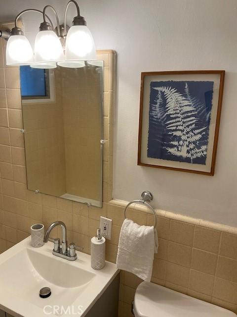 bathroom with tasteful backsplash, tile walls, vanity, and toilet