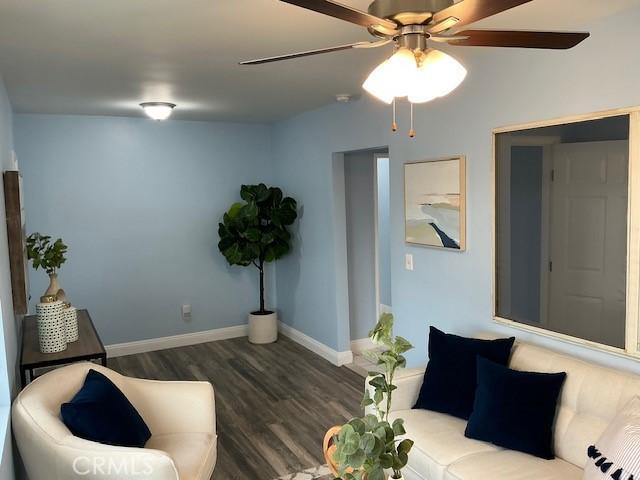 living area featuring baseboards, a ceiling fan, and wood finished floors