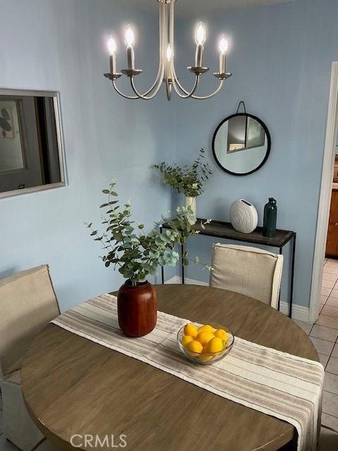dining area featuring a notable chandelier, baseboards, and light tile patterned flooring