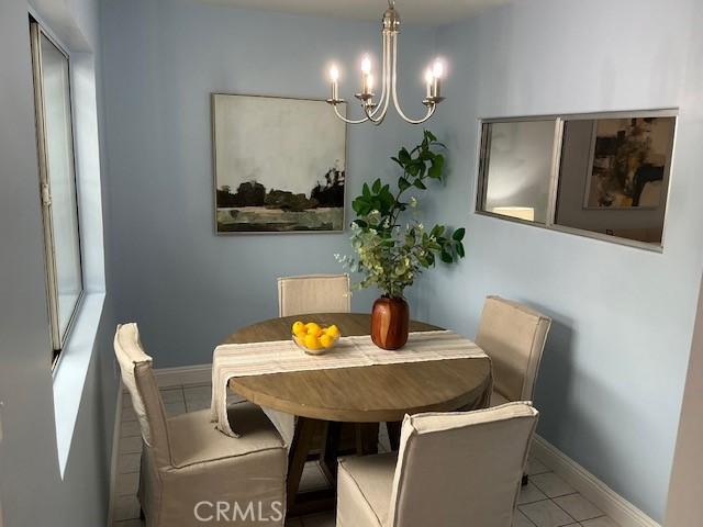 tiled dining room with baseboards and a notable chandelier