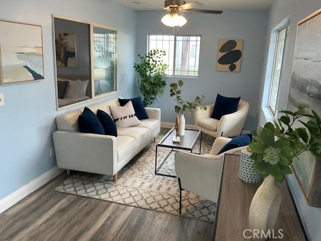 living room featuring wood finished floors, baseboards, and a ceiling fan