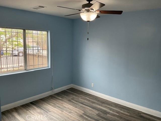 spare room featuring ceiling fan, baseboards, wood finished floors, and visible vents