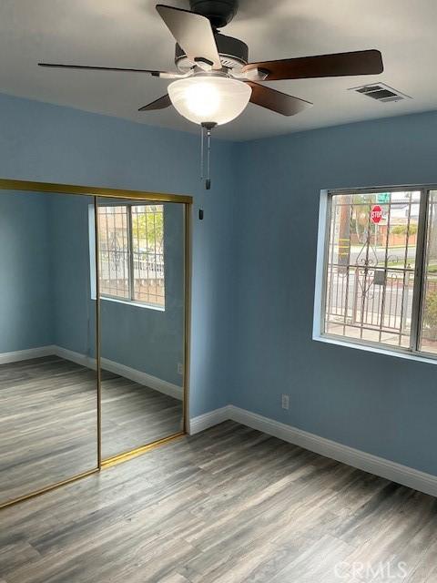 unfurnished bedroom featuring visible vents, baseboards, a closet, and wood finished floors