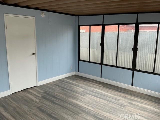 spare room with plenty of natural light, baseboards, and wood finished floors