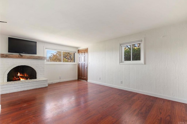 unfurnished living room featuring baseboards, a fireplace, and wood finished floors