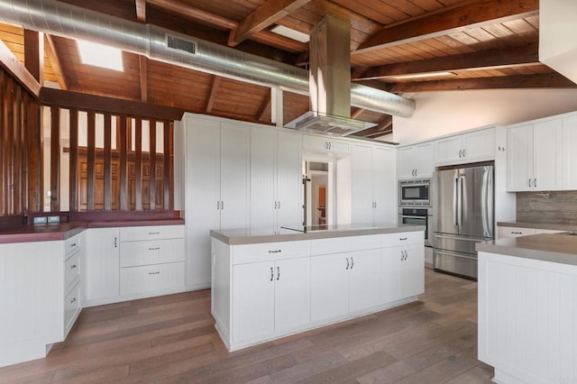 kitchen with vaulted ceiling with beams, wood finished floors, a center island, stainless steel appliances, and decorative backsplash