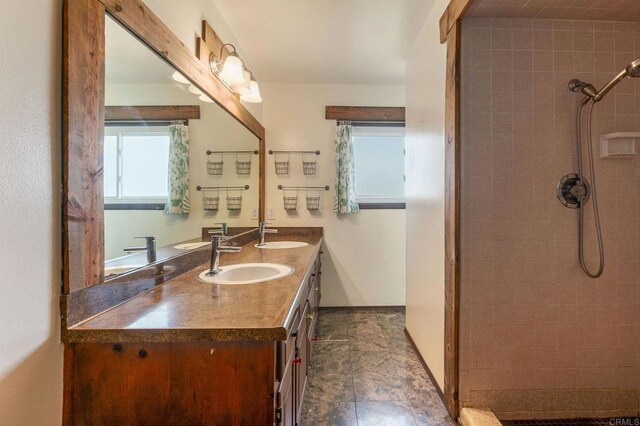 bathroom featuring double vanity, a sink, and tiled shower