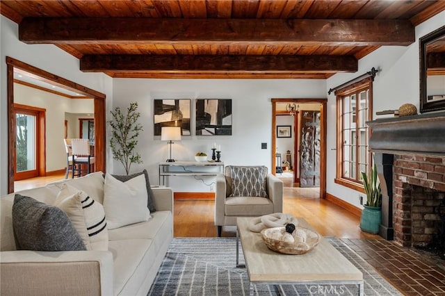 living room with beamed ceiling, wooden ceiling, a brick fireplace, and baseboards