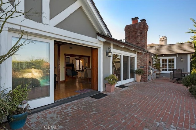 back of property featuring a patio area, stucco siding, and a chimney