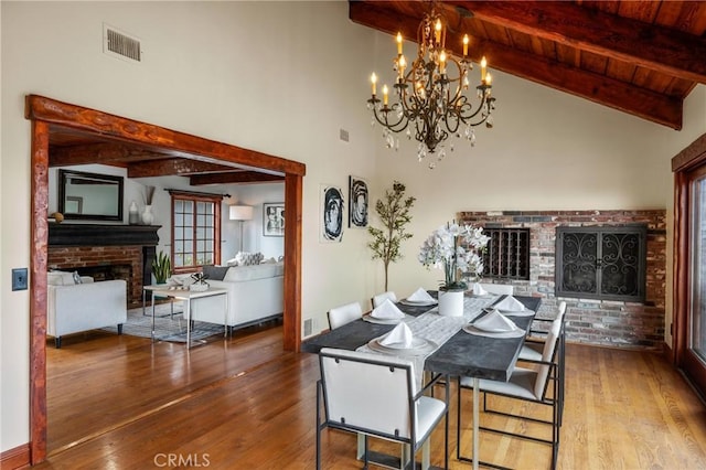 dining area featuring a chandelier, visible vents, wood finished floors, and a fireplace