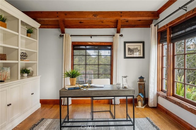 office space with light wood-style floors, baseboards, beam ceiling, and a healthy amount of sunlight
