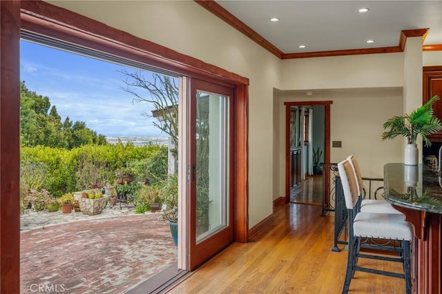 doorway featuring a wealth of natural light, light wood-style flooring, recessed lighting, and ornamental molding