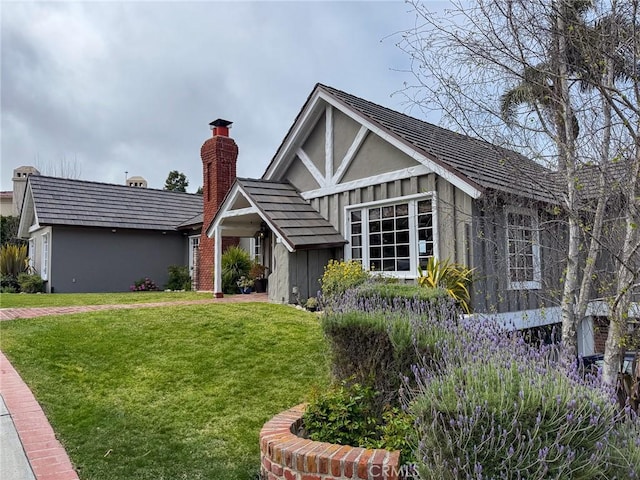 english style home featuring a chimney and a front lawn
