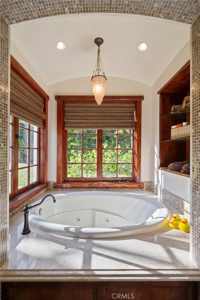 bathroom with recessed lighting, a jetted tub, and vaulted ceiling