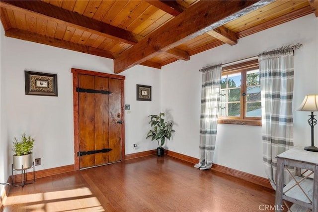 interior space with beamed ceiling, wooden ceiling, wood finished floors, and baseboards