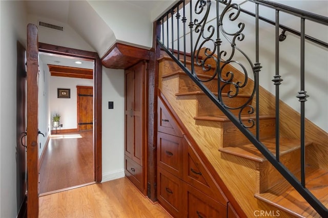 stairway with baseboards, visible vents, and wood finished floors