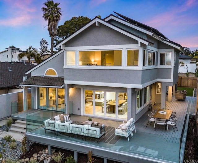 back of house with a deck, an outdoor living space, fence, outdoor dining area, and stucco siding