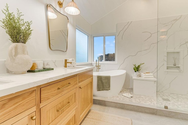 full bathroom featuring a freestanding bath, a sink, double vanity, tile patterned flooring, and lofted ceiling