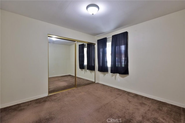 unfurnished bedroom with a closet, baseboards, and carpet