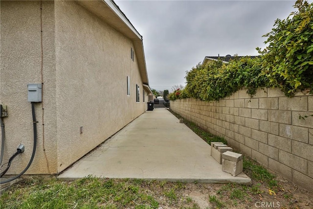 view of side of home with a fenced backyard, a patio, and stucco siding