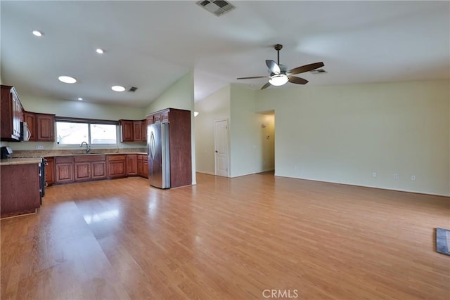 kitchen with visible vents, a sink, open floor plan, vaulted ceiling, and stainless steel appliances