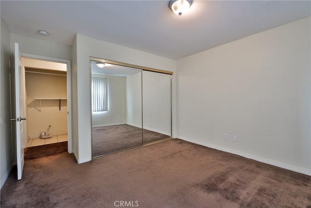 unfurnished bedroom featuring a closet, baseboards, and carpet