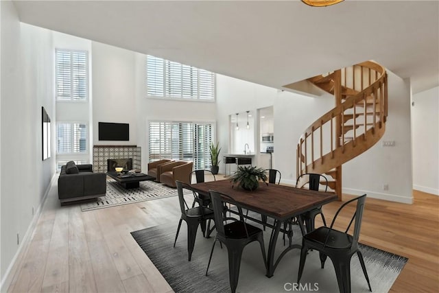 750 S Bundy Dr Unit 304, Los Angeles, CA 90049 - dining room featuring light wood-type flooring, baseboards, stairway, plenty of natural light, and a towering ceiling
