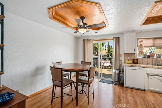 dining area featuring a textured wall, a textured ceiling, ceiling fan, and light wood-type flooring