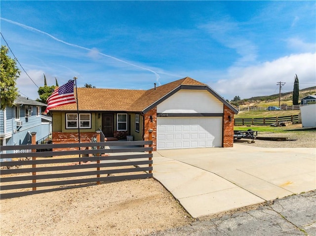 view of front of house featuring brick siding, a fenced front yard, concrete driveway, and a garage