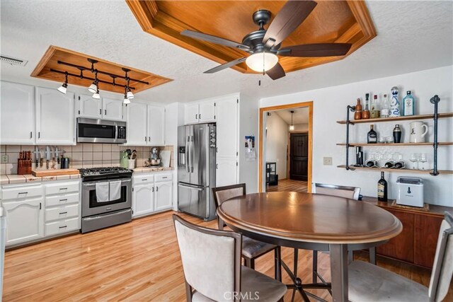 kitchen with white cabinets, visible vents, stainless steel appliances, and tile counters