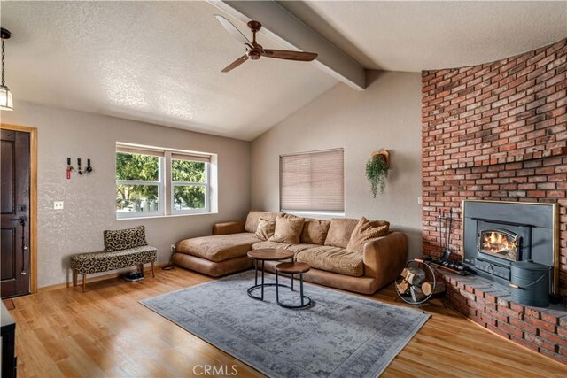 living area featuring a ceiling fan, vaulted ceiling with beams, a textured ceiling, and wood finished floors