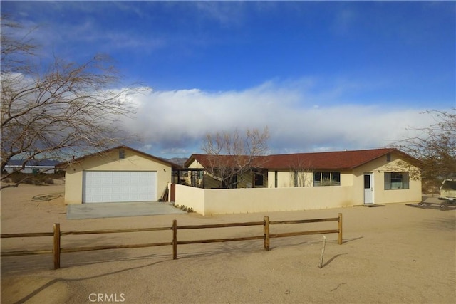 single story home featuring driveway, a fenced front yard, a garage, and stucco siding