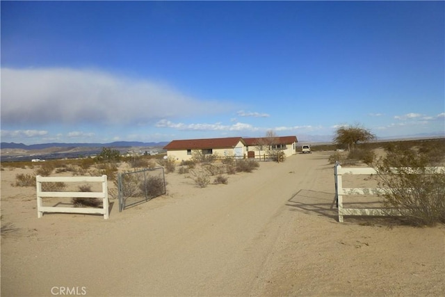 exterior space featuring dirt driveway, a mountain view, a rural view, and a gated entry