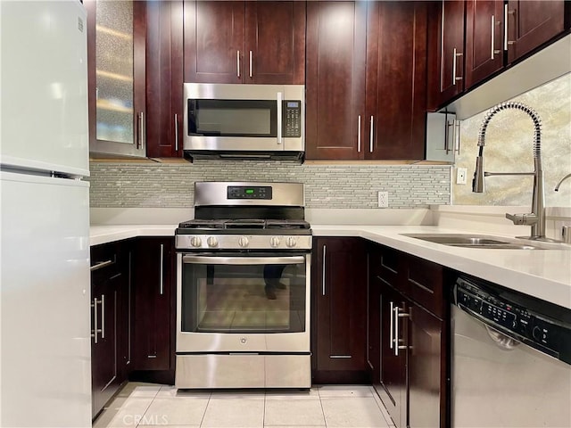 kitchen with light tile patterned floors, stainless steel appliances, light countertops, and a sink