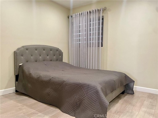 bedroom with baseboards and wood finished floors