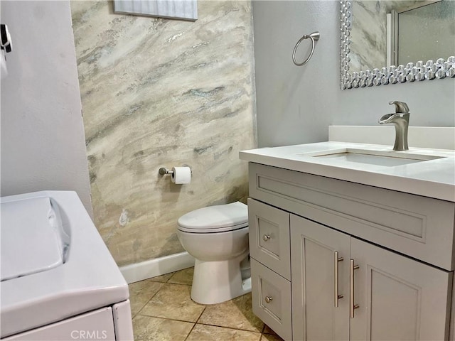 bathroom featuring tile patterned flooring, baseboards, toilet, and vanity