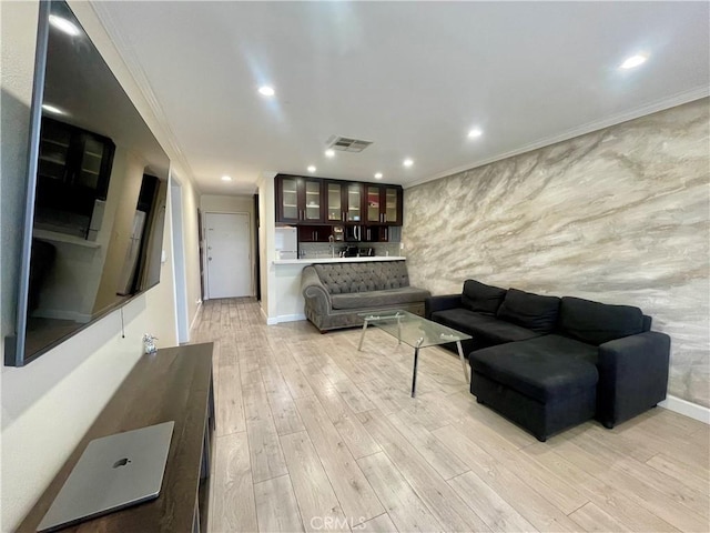 living area with light wood-type flooring, baseboards, ornamental molding, visible vents, and recessed lighting