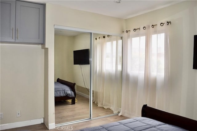 bedroom featuring baseboards, wood finished floors, and a closet