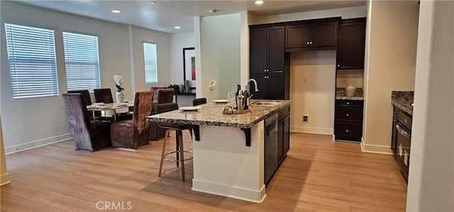 5232 Las Palmas Way, Chino, CA 91710 - kitchen with a sink, light stone countertops, light wood-style floors, a kitchen breakfast bar, and baseboards