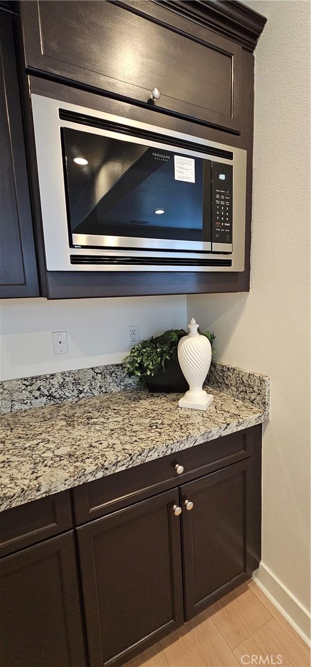 5232 Las Palmas Way, Chino, CA 91710 - kitchen view of stainless steel microwave, baseboards, dark brown cabinetry, and light stone countertops