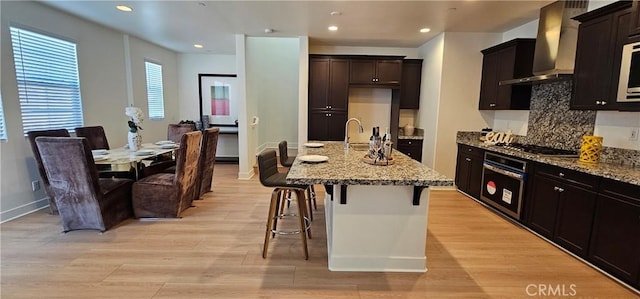 5232 Las Palmas Way, Chino, CA 91710 - kitchen with stainless steel appliances, wall chimney range hood, light stone counters, light wood-style floors, and tasteful backsplash