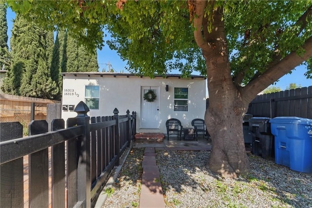 bungalow-style house featuring stucco siding, a patio, and fence private yard